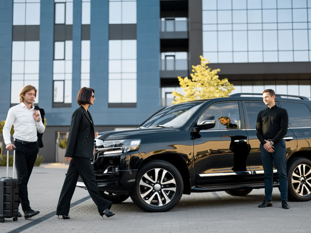 Professional chauffeur opening the door of a luxury black car